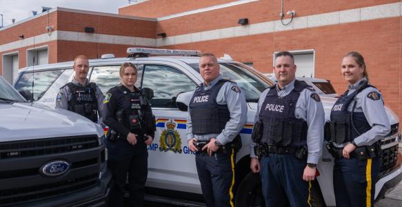 Members of Okotoks Municipal Enforcement and RCMP stand in front of a police car