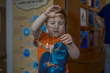 Young child holds up his dreamcatcher at Nature Friday event