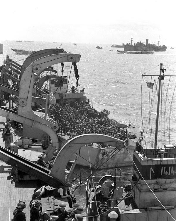 Photo of a large ship with many men lined up waiting to get off to storm the beaches at Normandy.