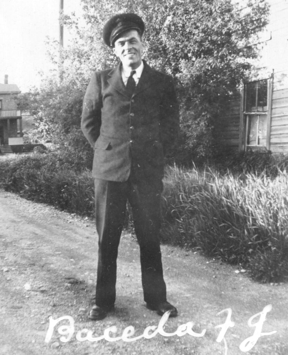 Black and white photo of a smiling man in a suit standing on grass.