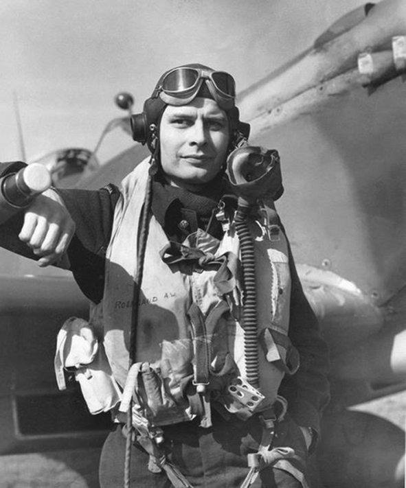 Arnold Roseland wearing his flight gear standing in front of a plane during World War Two.