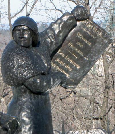 Bronze statue of a woman holding a newspaper with the headline "Women are persons..."