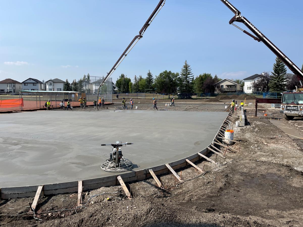 cement pouring concrete into outdoor boarded rink 