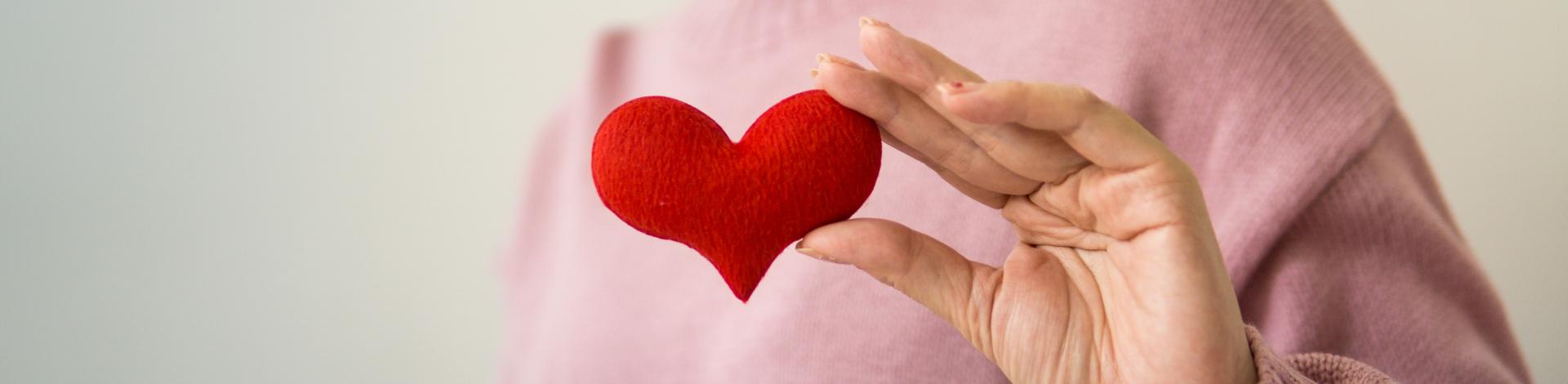 woman holding red felt heart in her hand to show care