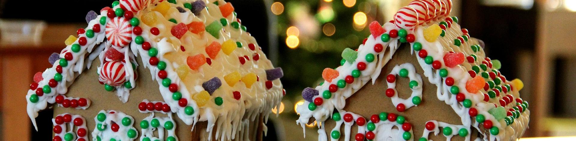 Two decorated gingerbread houses with a Christmas tree in the background.