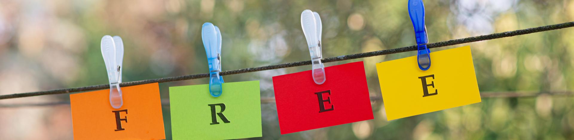 word-free-spelled-colorful-papers-hanging-rope-attached-by-clothes-peg-outside-green-nature