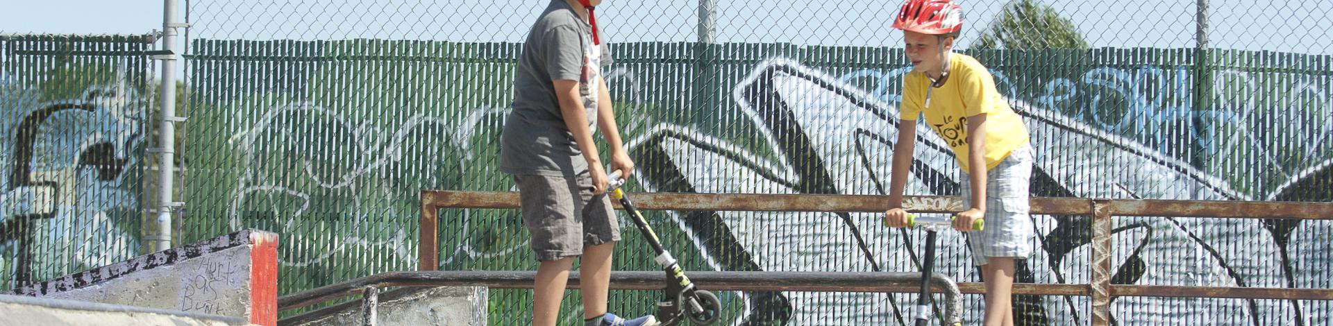 two kids on scooters at Okotoks skate park