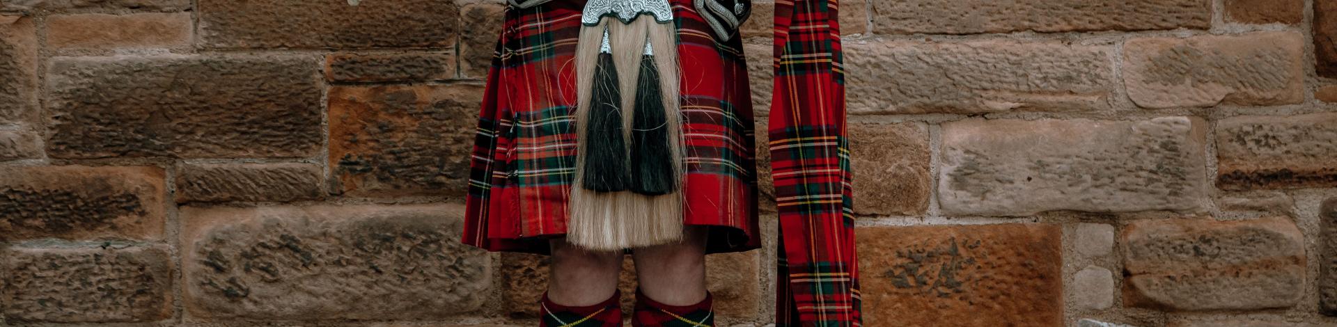 male-wearing-traditional-scottish-kilt-standing-front-wall