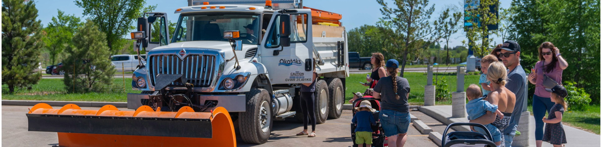 a snowplow with some families looking at it on a sunny day