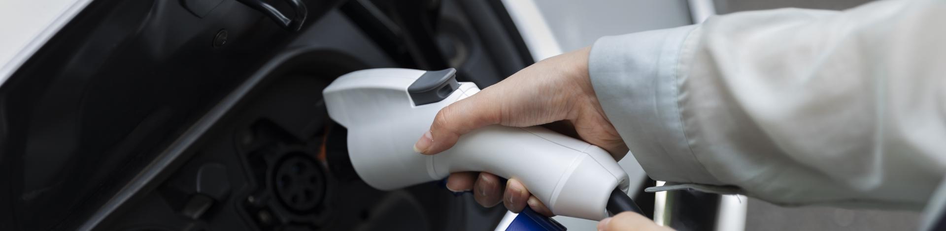 Woman holding charge port to charge her electric vehicle 