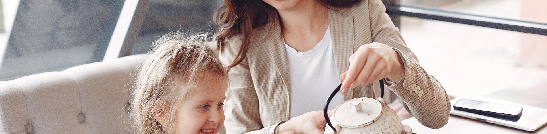 Mother serving young daughter tea from a tea pot 