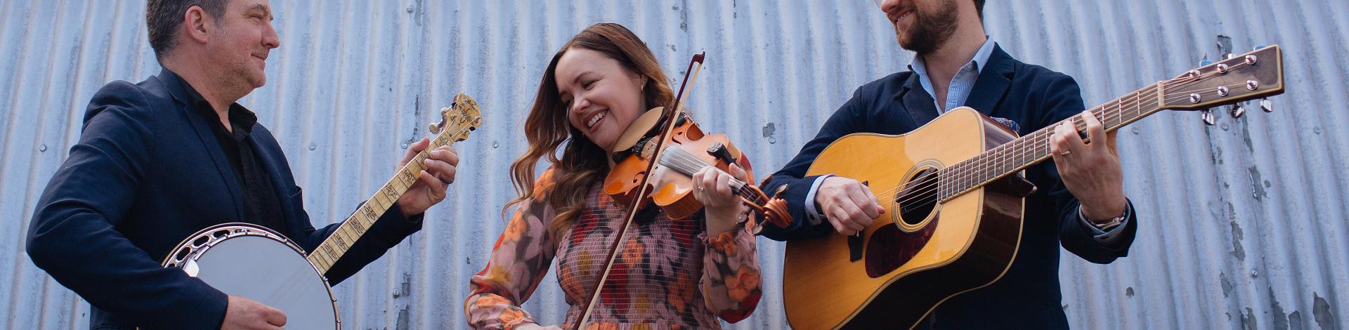 three musicians play in front of a gain silo