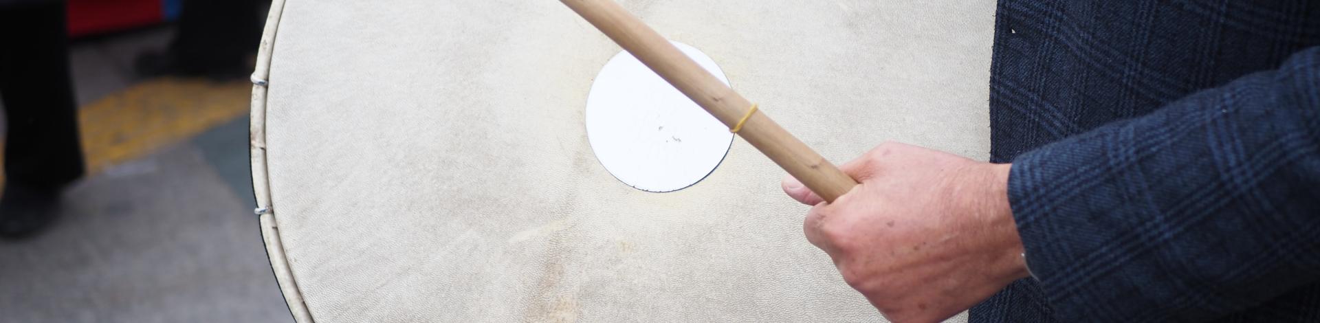 a man hits an old drum with a beater