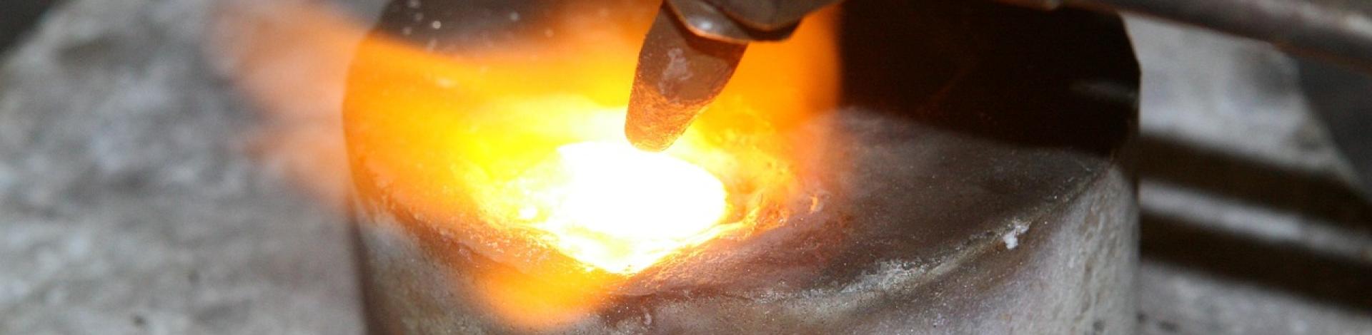 An acetylene torch is melting metal in a stone mould.