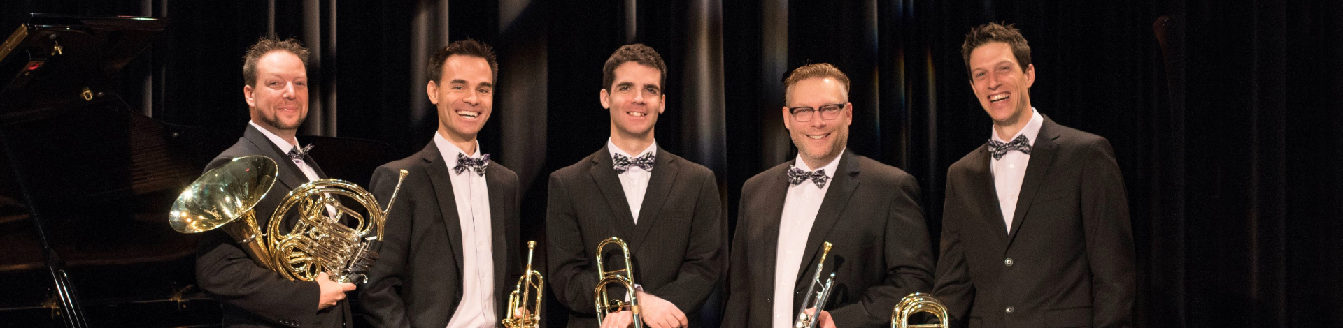 Five brass band members standing in tux
