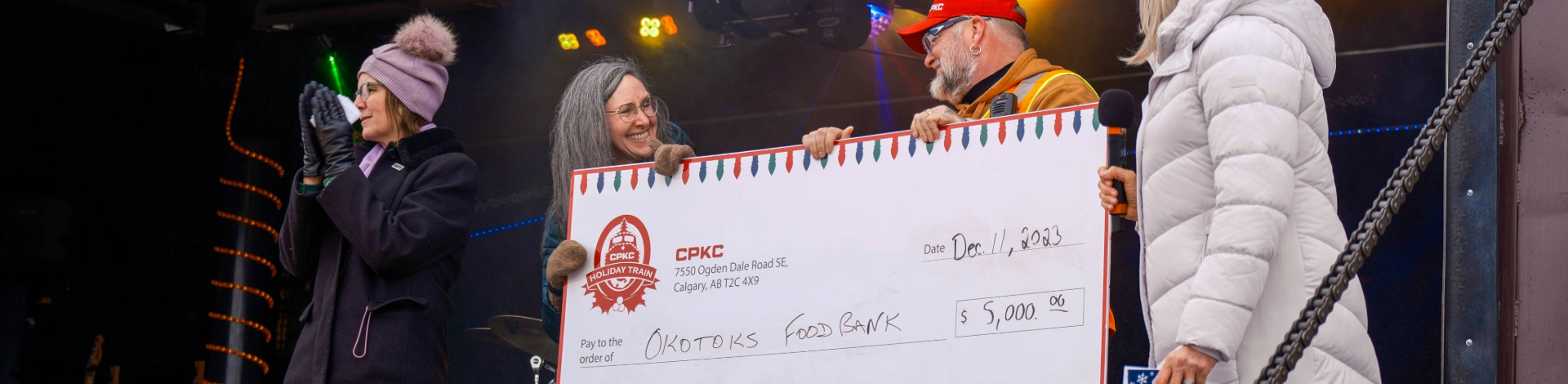 Three people holding a large cheque