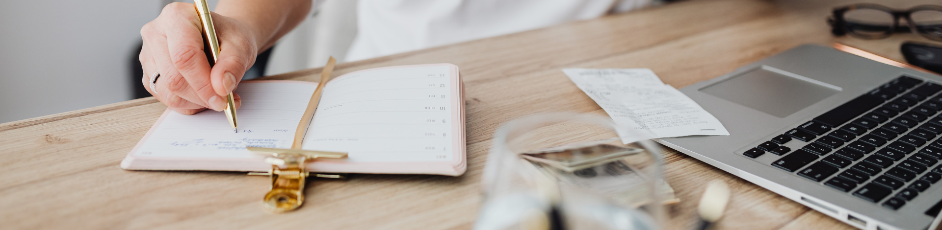 an open notebook with a computer and receipts and money stacked beside