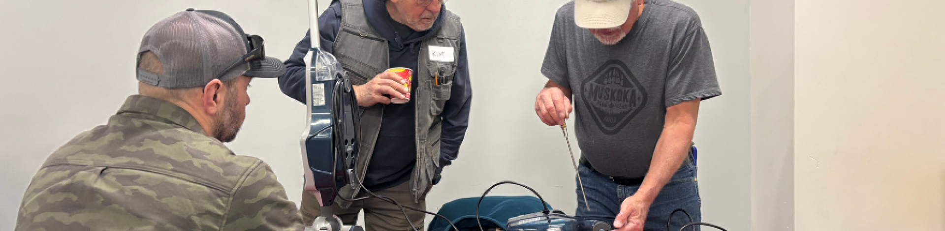 Two men repair a vaccum at a Repair Cafe