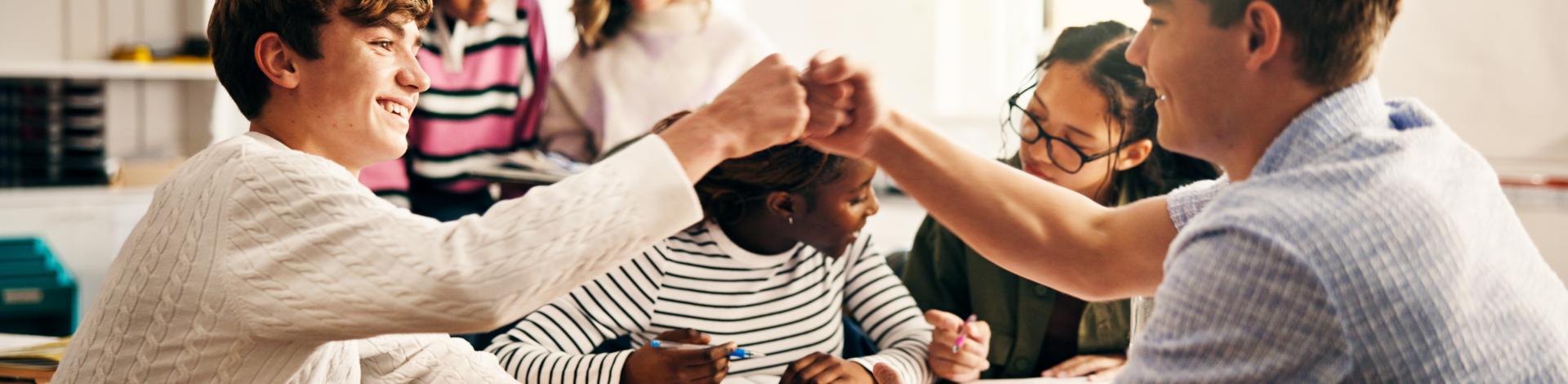 student in classroom with fist bump, success and collaboration