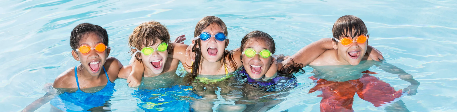 five children smiling in a pool wearing goggles