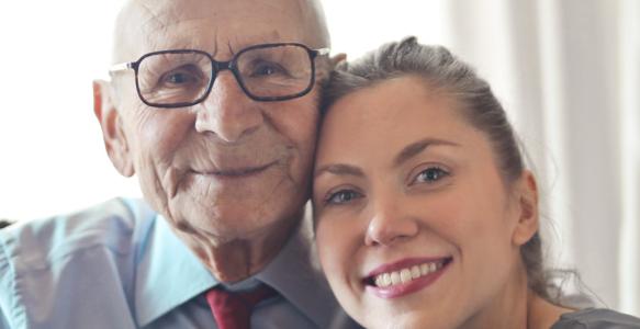 Happy senior man and young adult woman hugging and smiling