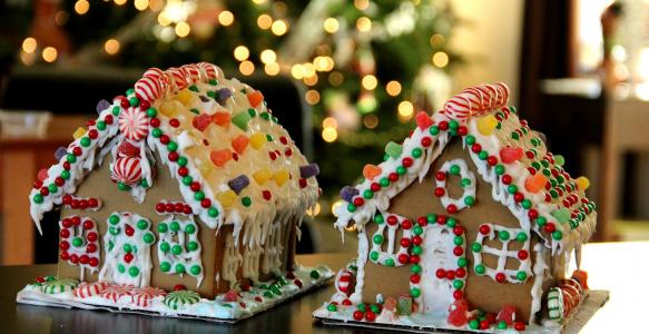 Two decorated gingerbread houses with a Christmas tree in the background.