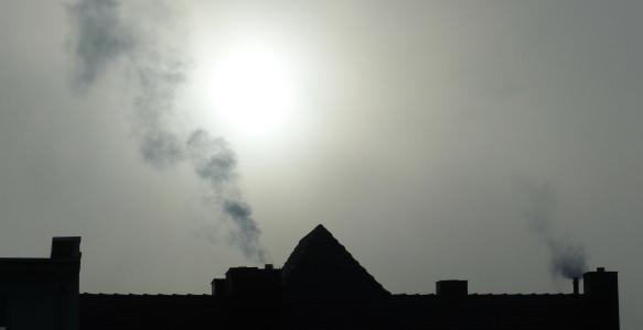 A black silhouette of a rooftop outlined against a smoky sky. 
