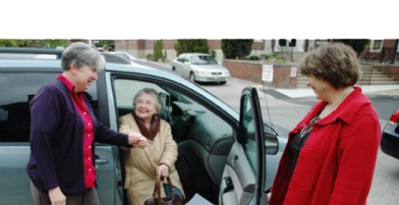 Volunteer women helping lady get out of the vehicle