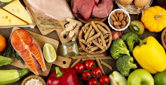 Assortments of food including dried pasta, vegetables, raw salmon, chicken and beef