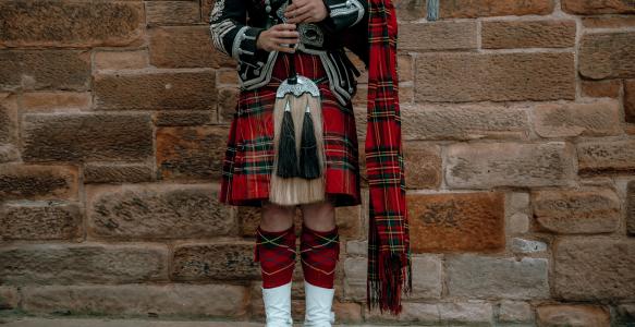 male-wearing-traditional-scottish-kilt-standing-front-wall