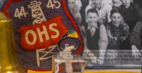 a photo of old school items including a class ring, old class photo and a hand bell
