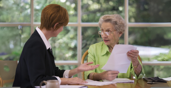 Woman helping senior lady with paperwork