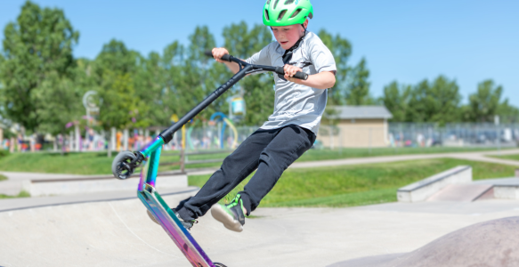 Young boy performing a scooter trick at an outdoor skatepark