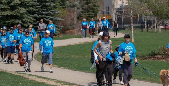 people in blue shirts walk pathways. The shirts say "hike for hospice"