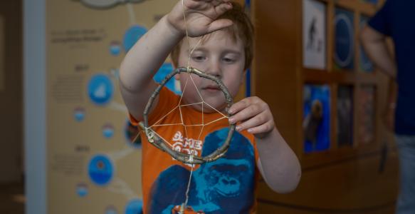 Young child holds up his dreamcatcher at Nature Friday event