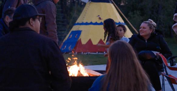 People gathered around a firepit in front of Okotoks Tipi for Fireside Stories 