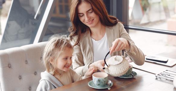 Mother serving young daughter tea from a tea pot 