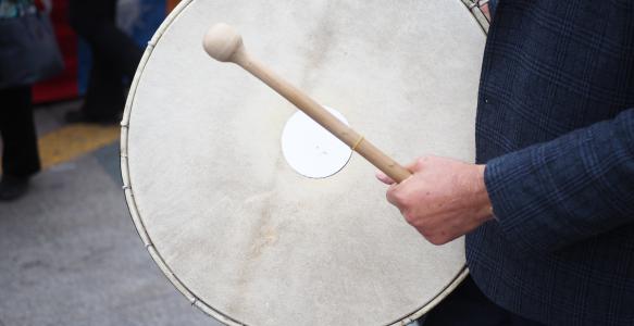a man hits an old drum with a beater