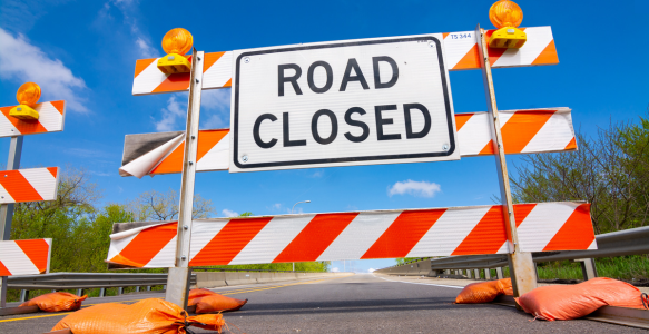 Orange road closed sign with blue sky in background