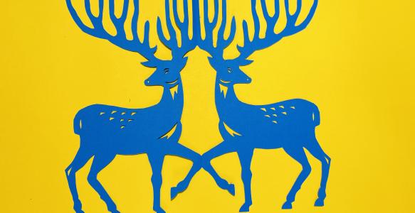 Two blue stags made of paper on a yellow background.