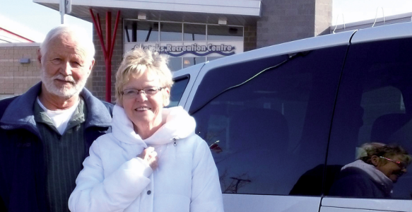 two volunteers drivers stand next to a van