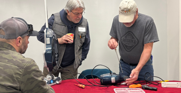 Two men repair a vaccum at a Repair Cafe