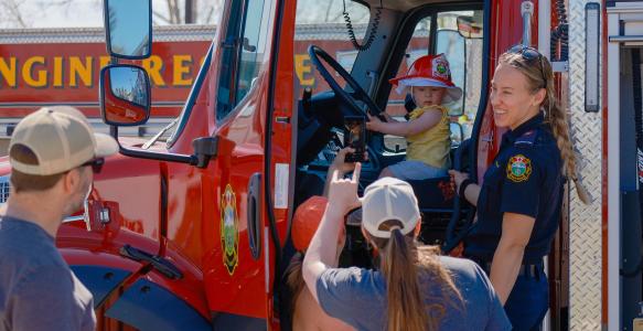Okotoks Fire fighter stands in front of fire truck at emergency preparedness week open house 