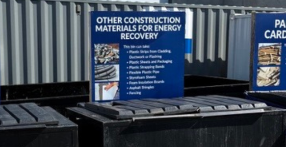 Three recycling bins at a construction site