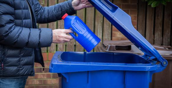 Man outside with blue recycling bin