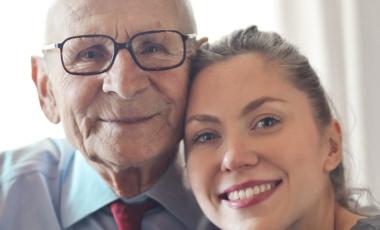 Happy senior man and young adult woman hugging and smiling