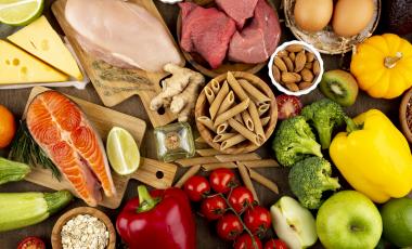 Assortments of food including dried pasta, vegetables, raw salmon, chicken and beef 