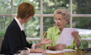 Woman helping senior lady with paperwork