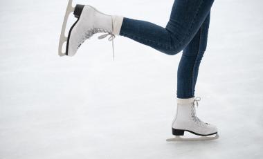 Person wearing white figure skates glides on ice 