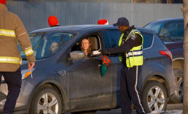 Okotoks Municipal Enforcement collecting donations from a stopped vehicle on the road 